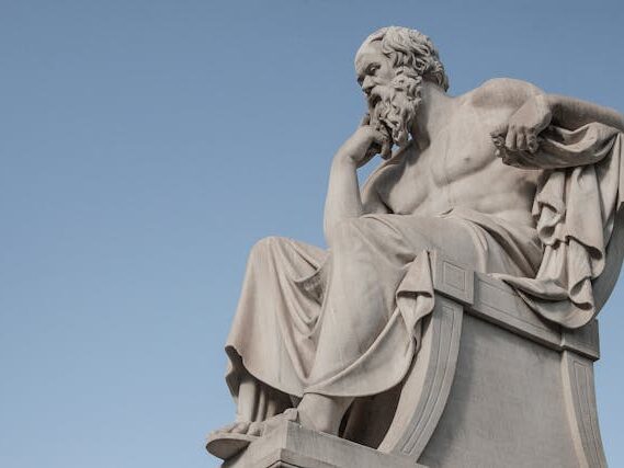 Estatua de piedra del filósofo Sócrates en actitud pensativa, representando el diálogo socrático aplicado en la terapia psicológica.