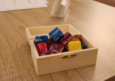 Una pequeña caja de madera abierta con caramelos sobre una mesa de consulta, un detalle de bienvenida para los pacientes en terapia.