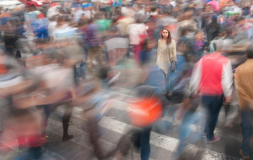 Persona quieta entre una multitud en movimiento, representando la agorafobia y el miedo a espacios concurridos